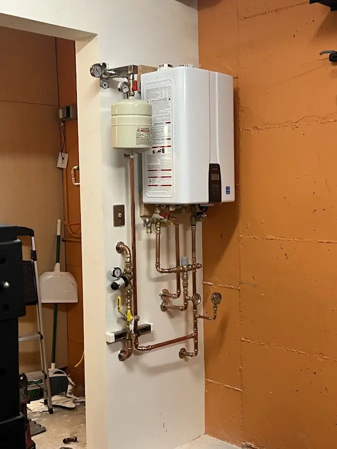 Plumbing technician inspecting water heater connections in Fulton